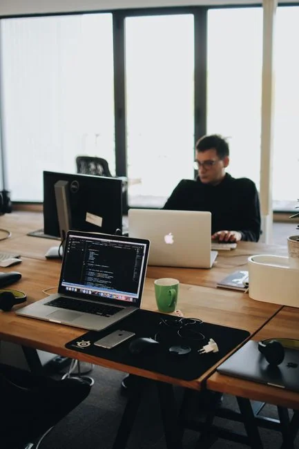 why-choose-us A sleek office desk setup featuring Apple devices: iMac, MacBook, and iPad.